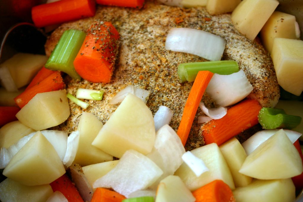 Vegetables on top of a raw chicken in an instant pot