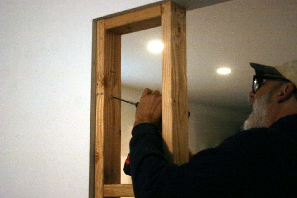drilling a wooden frame into a wall