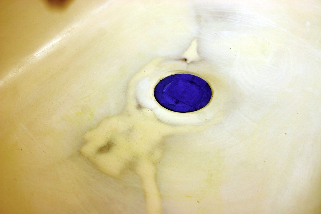 painter's tape over the drain in an old cast iron sink